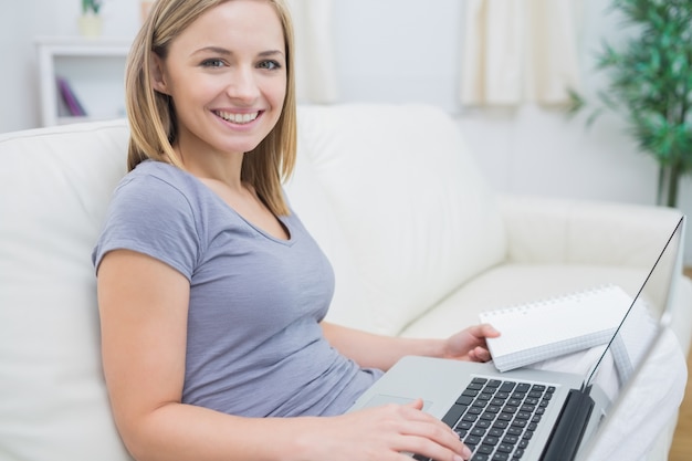 Casual vrouw met laptop en boek in de woonkamer