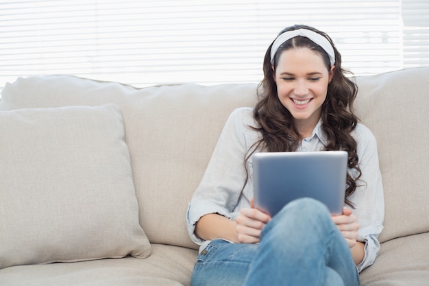 Casual woman on cosy couch using tablet pc