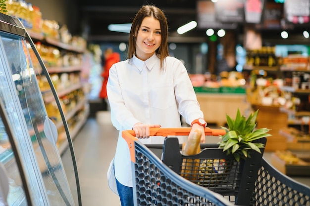 Повседневная женщина делает покупки в продуктовом магазине и выглядит счастливой