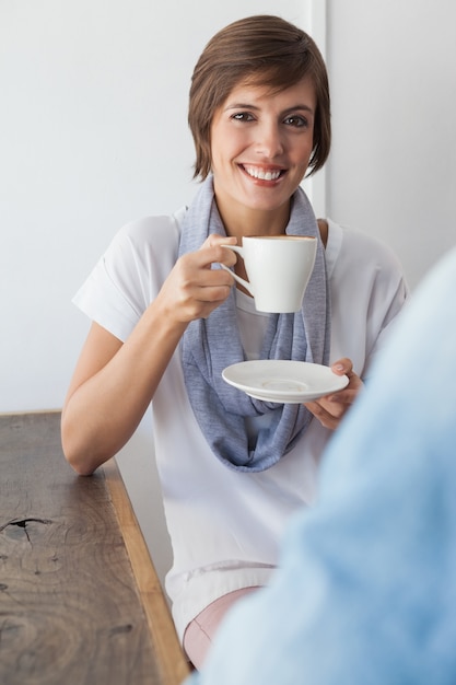 カジュアルな女性がコーヒーを持っている友人