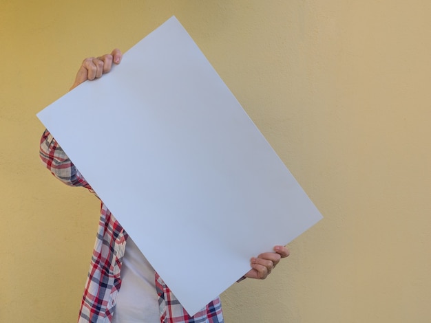 casual woman hiding her face behind a blank billboard. copy space