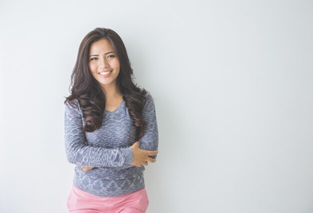 Casual woman smiling leaning on white wall