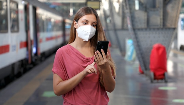 Casual woman using smart phone in train station