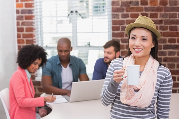 Casual woman with colleagues behind in office