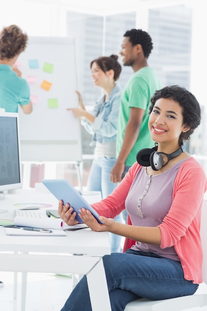 Casual woman with group of colleagues behind in office