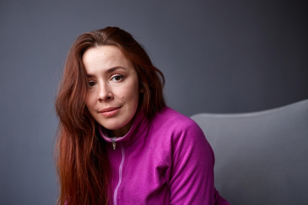 Casual woman with red hair on grey background