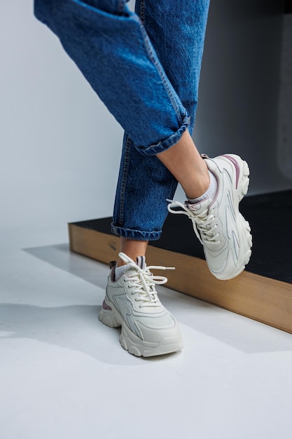 Casual women's fashion Sports shoes for women Slender female legs in jeans and white stylish casual sneakers Women's comfortable summer shoes