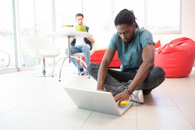 Casual young man using laptop on floor