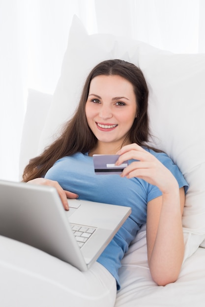 Casual young woman doing online shopping in bed