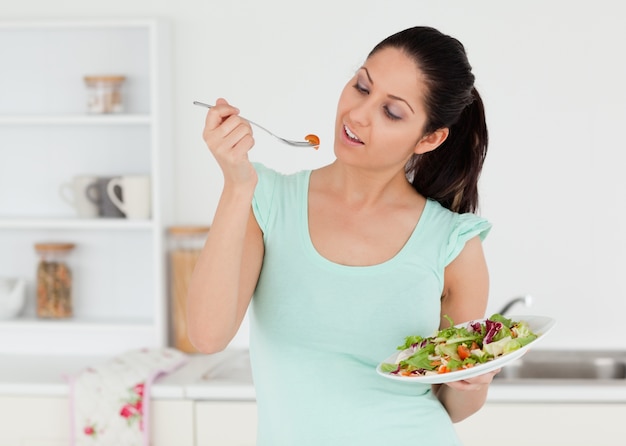 Giovane donna casuale che mangia insalata