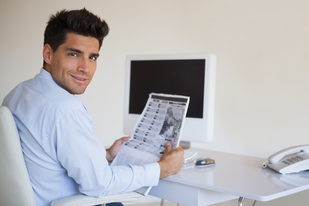 Foto casual zakenman krant lezen op zijn bureau