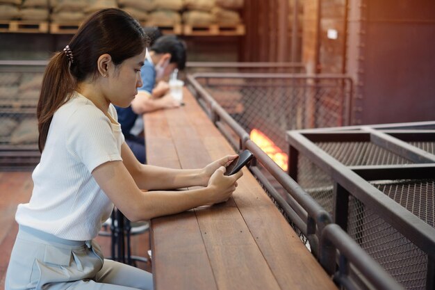 Casual zakenvrouw die smartphone vasthoudt en gebruikt voor sms-berichten jonge vrouw touchscreen mobiele telefoon typt in café of moderne kantoorlevensstijltechnologie Sociale media en netwerkconcept