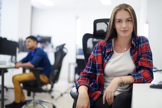 casual zakenvrouw die werkt op een desktopcomputer in een modern open startbureau-interieur