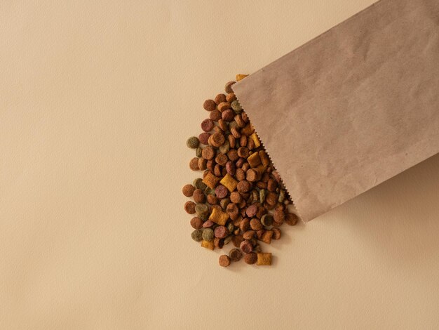 Photo cat or dog food is scattered from a paper bag on beige a place for text