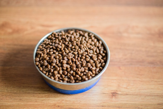 Cat food in bowl on wooden background, top view