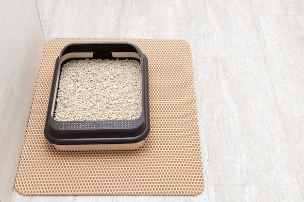 Cat litter box with wooden pellets on litter mat in bathroom toilet for domestic pets