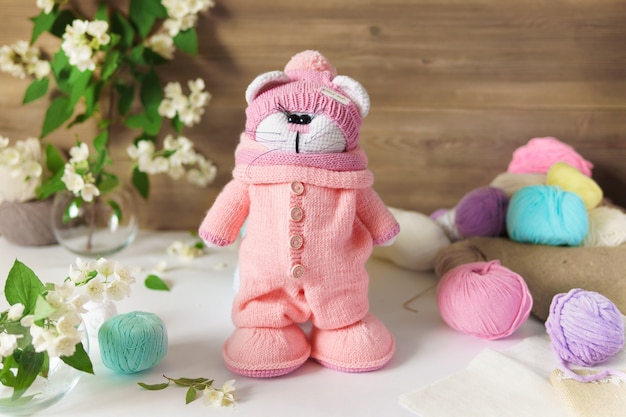 A cat made of wool thread. Handmade knitted stuffed toy on a wooden table.