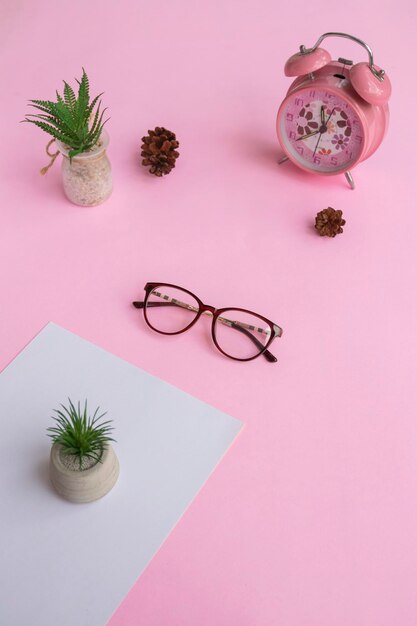 Cat's eye-bril op de foto van bovenaf met een minimalistisch concept op een paarse papieren achtergrond met een wekkerdecoratie en droge bladeren