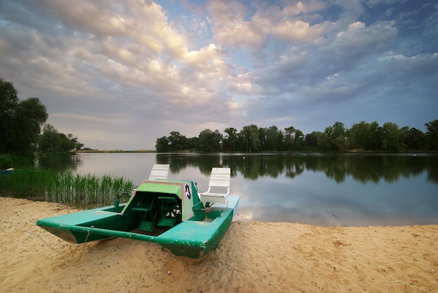 Catamaran aan de oever van de rivier bij zonsondergang.