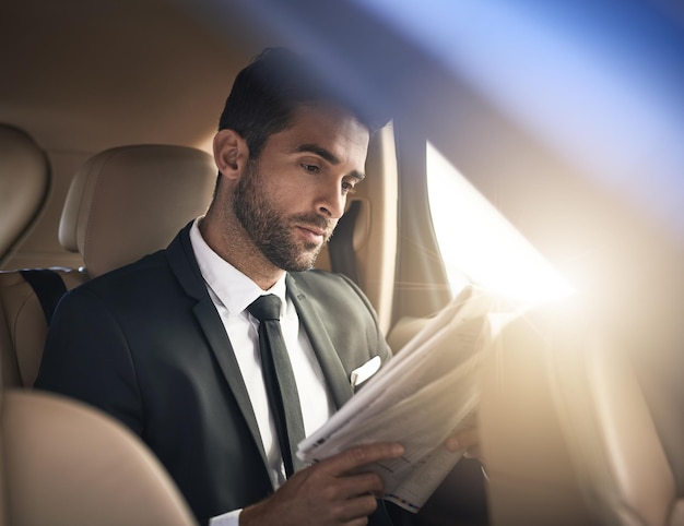 Catching up on the latest news Cropped shot of a handsome young businessman reading the paper while on his morning commute to work