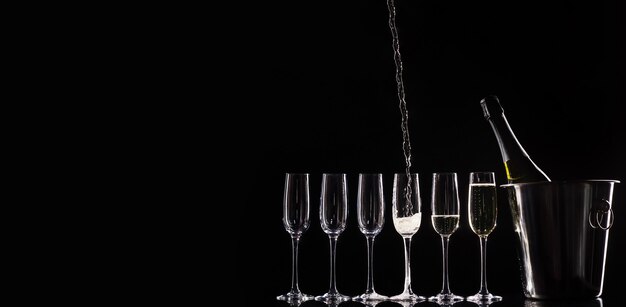 Catering service. Silhouette with bottle of champagne in a bucket and glasses. Pouring champagne.