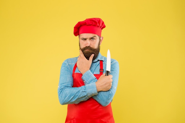 Catering voor iedereen Professionele chef-kok met mes uitstekende kok of bakker speciale aanbieding van chef-kok in restaurantkeuken volwassen mannelijke chef-kok op gele achtergrond serieuze man koken op keuken