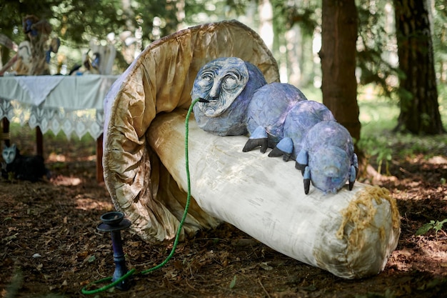 Caterpillar smoking hookah from Alice wonderland art object outdoor art exhibition in green forest