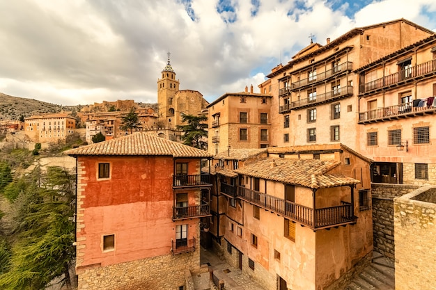 Cathedral of the city elevated over the blue sky with clouds. ancient construction with stone walls and medieval architecture. albarracã­n teruel spain. aragon.