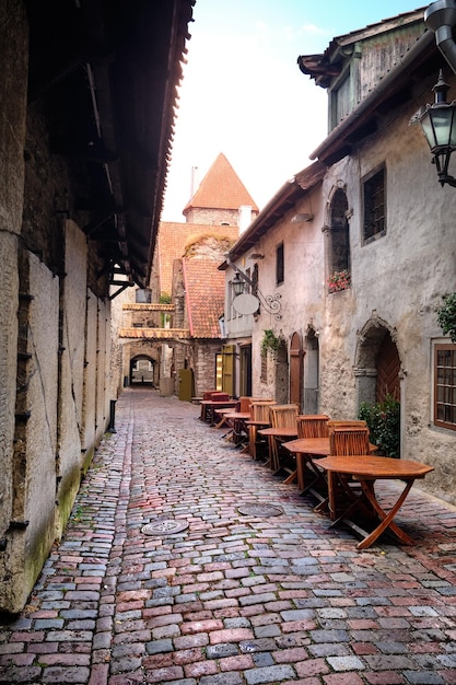 Catherine Lane in Tallinn Estonia on a rainy day Wet tables and chairs of outdoor cafe on this ancient cobbled lane in historic district of Old Town Tallinn Estonia