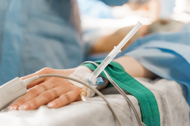 Photo catheter safely inserted into woman hand on plastic operation anesthesia for surgery.