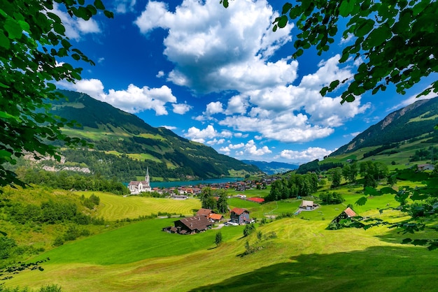 Catholic church, traditional wood and modern houses along the lake Lungernsee in swiss village Lungern, canton of Obwalden, Switzerland