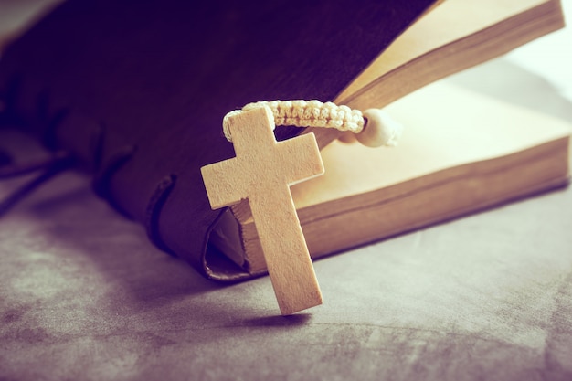 Il rosario cattolico borda con il vecchio libro sulla preghiera della tavola del cemento, concetto del fondo del rosario nel tono d'annata.