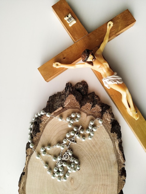 Catholic rosary for prayer and crucifix on white and wooden background