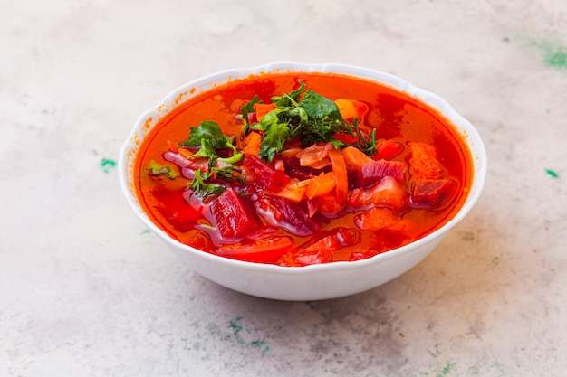 Caturated borscht with large slices of different vegetables and greens on top