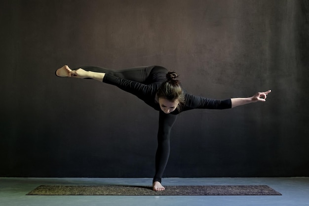 Caucasain girl standing in yoga asana vbalance on foot