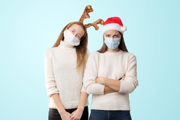 Caucasiam jonge vrouwen met kerstmuts en rendieren medische masker dragen.