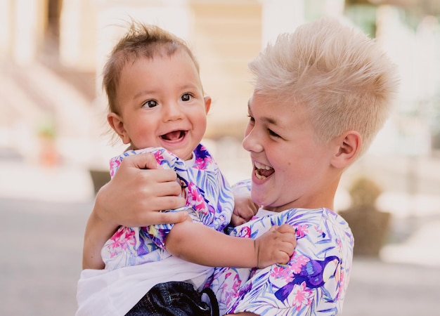 caucasian adorable cute boys siblings holding each other in sunny day outdoor Family help support