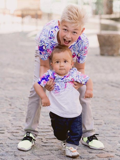 caucasian adorable cute boys siblings holding each other in sunny day outdoor Family help support