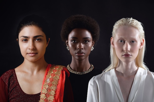 Caucasian and african american young woman isolated on black background.