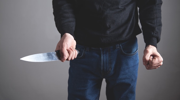 Caucasian aggressive man threatening with fist and holding knife.