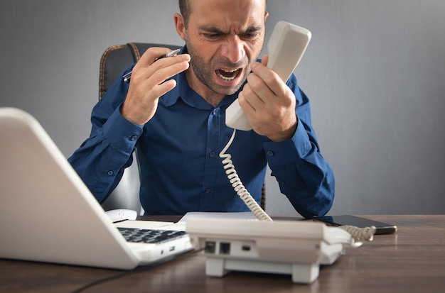 Caucasian angry businessman screams into the telephone receiver