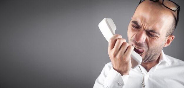 Caucasian angry businessman screams into the telephone receiver