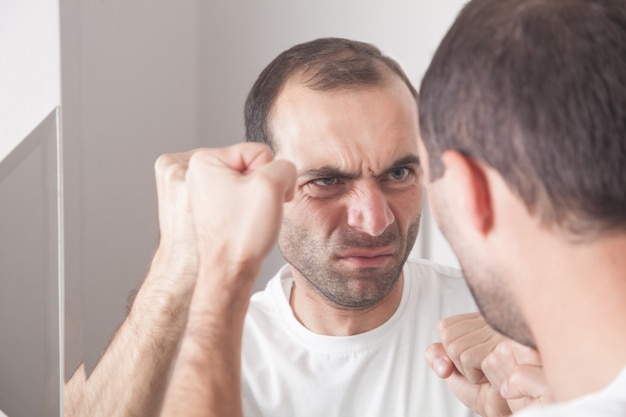 写真 鏡で見ている白人の怒っている男