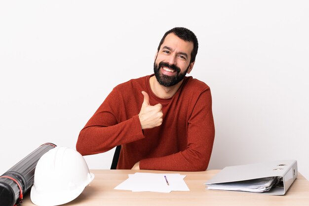 Caucasian architect man with beard in a table giving a thumbs up gesture.