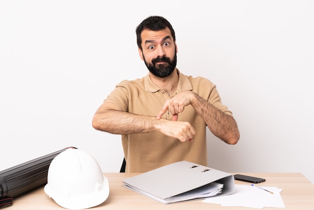 Caucasian architect man with beard in a table making the gesture of being late.