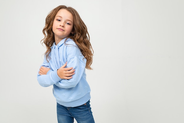 Caucasian attractive teenage girl in a blue hoodie crossed her arms in front of herself on a light with copy space