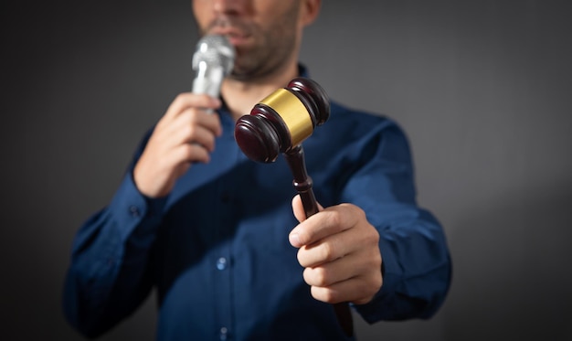 Caucasian auctioneer holding microphone and gavel