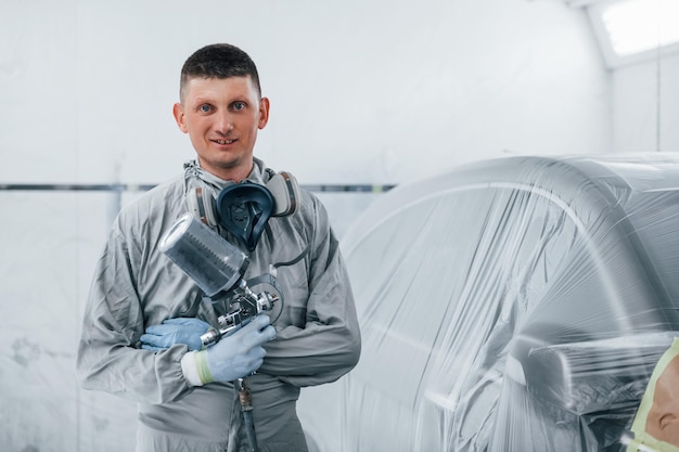 Кавказский авторемонтник в форме работает в гараже