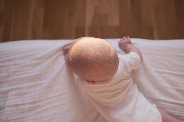 Caucasian baby crawling to the edge of the bed.