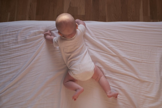 Caucasian baby crawling to the edge of the bed.